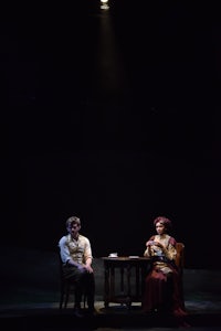 two people sitting at a table on stage