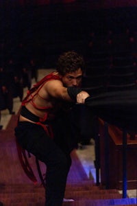 a man wearing a black and red cloak on a stage