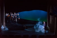 a group of people standing on a stage with smoke in the background