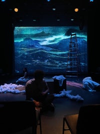 a group of people sitting on chairs in front of a large screen