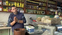 a man standing in front of a counter with jars of food